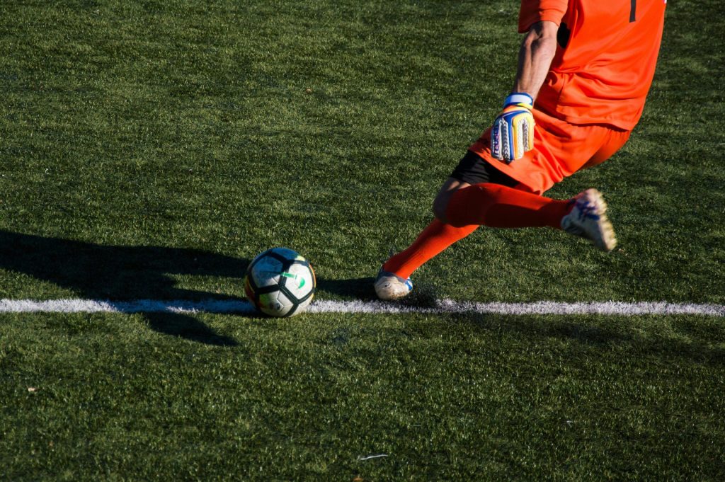 Hombre pateando un balón de fútbol en el campo.
